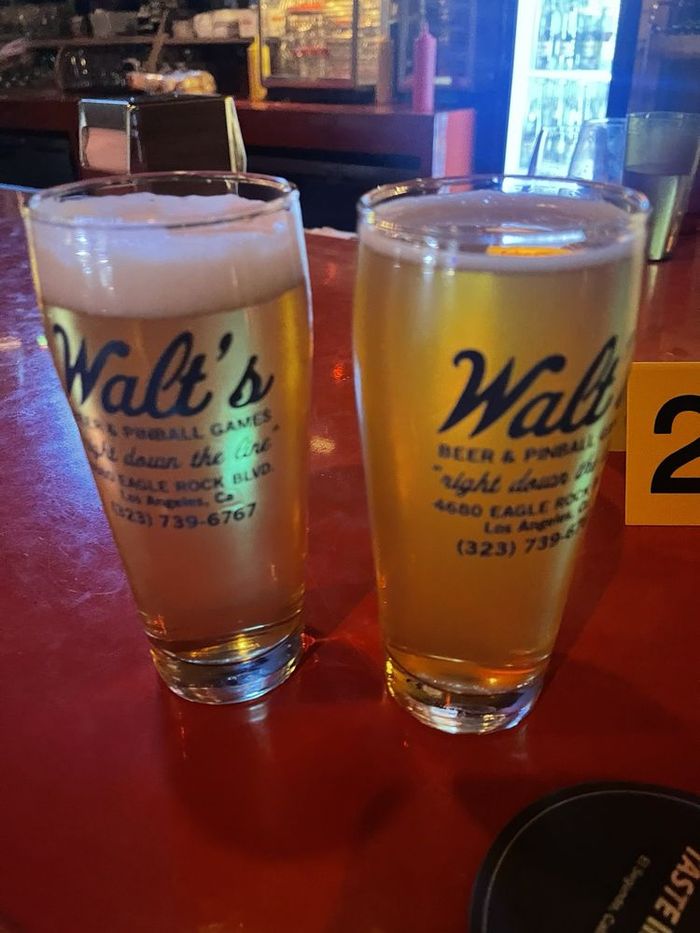 Two Walt's pint glasses of beer on the bar