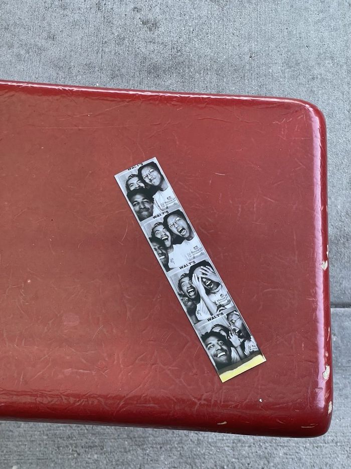 A photo booth picture strip lying on a red table